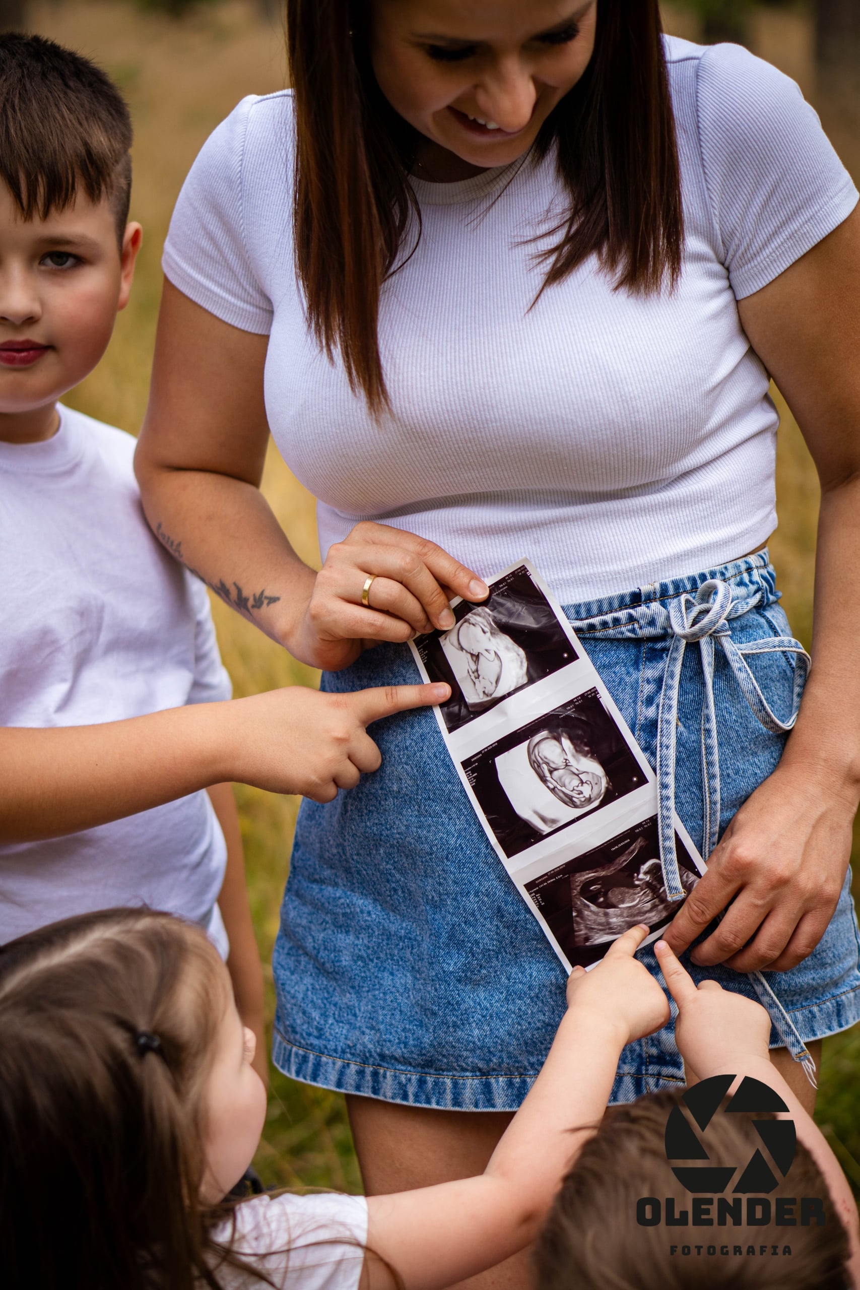 Mama w ciąży pokazuje dzieciom wydruk badania USG