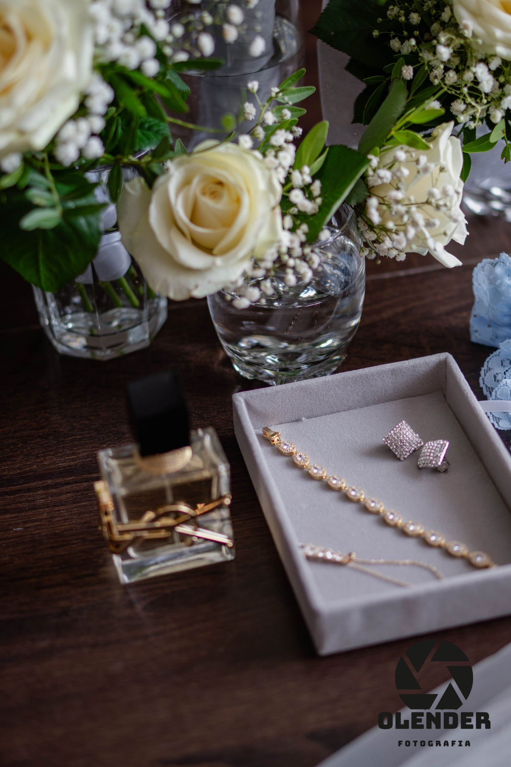 Biżuteria, perfumy i białe róże panny młodej na stole