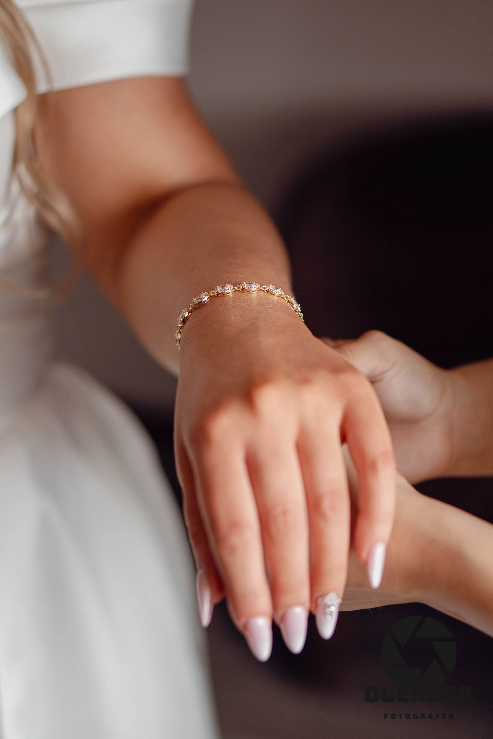 Dłoń panny młodej z cienką bransoletką i jasnym manicure