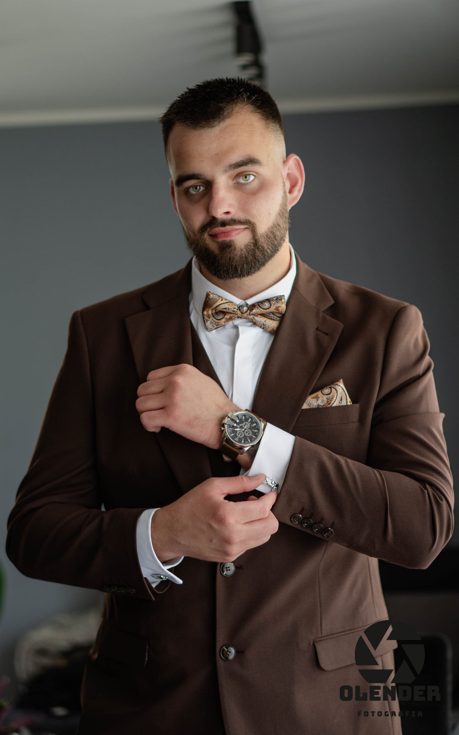 Pan młody zapina mankiet i patrzy prosto w obiektyw