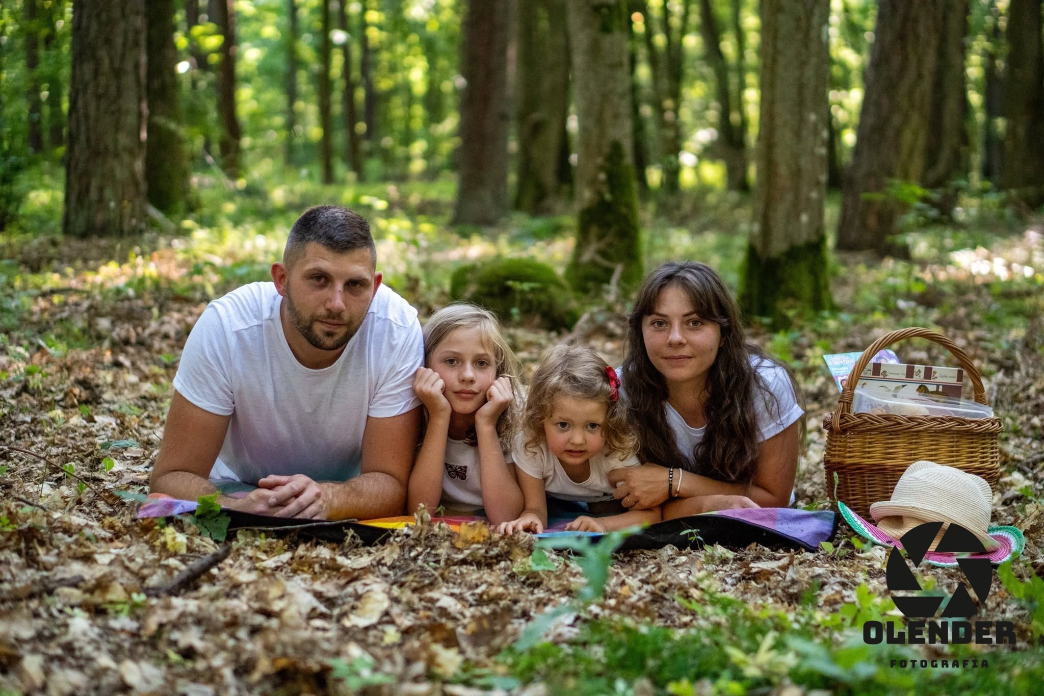 Rodzice z dwiema córkami leżą na kocu wśród liści